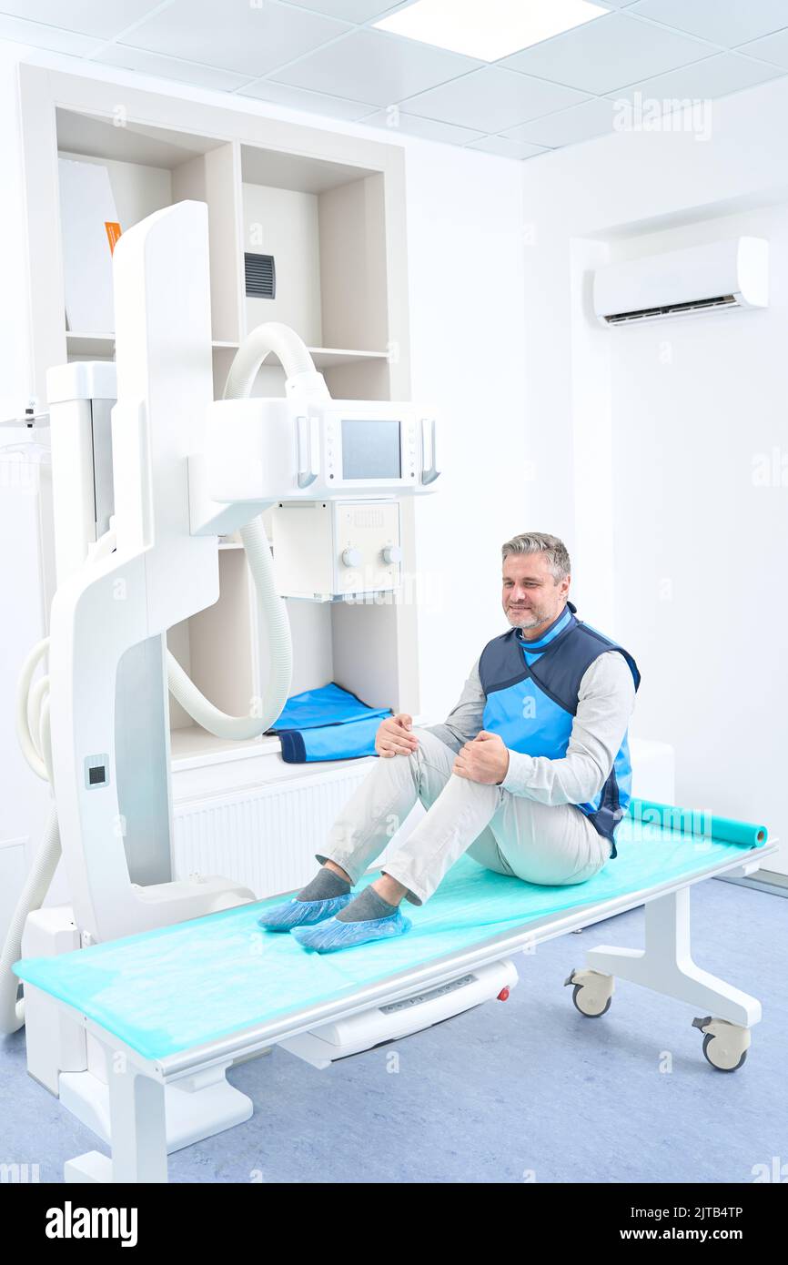 Man in lead shield sitting on x-ray machine Stock Photo