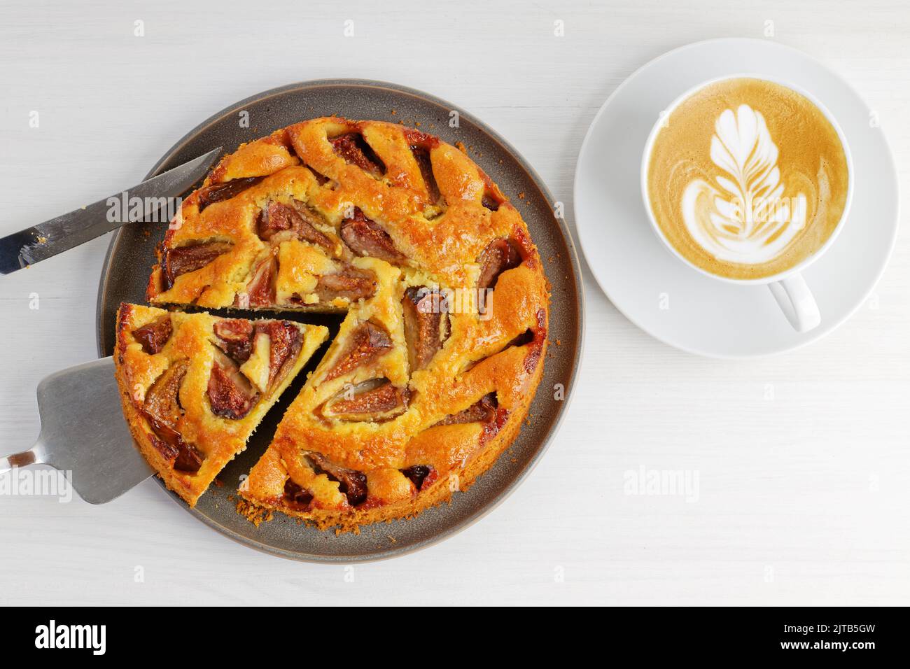 Closeup homemade fig pie and cup of coffee cappuccino on white wooden table. Top view. Stock Photo