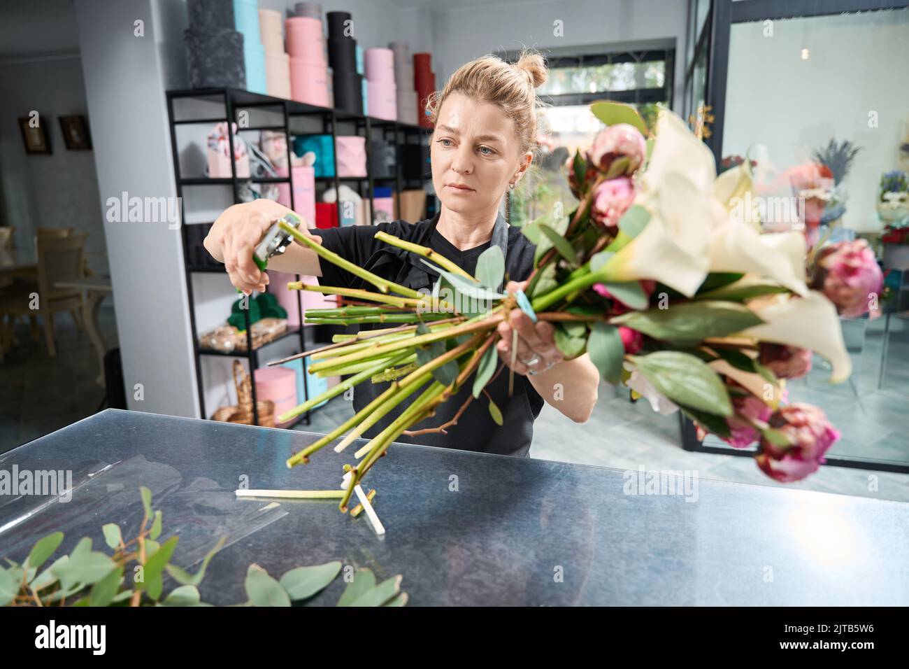 Focused female florist trims edges of stems in bouquet Stock Photo Alamy