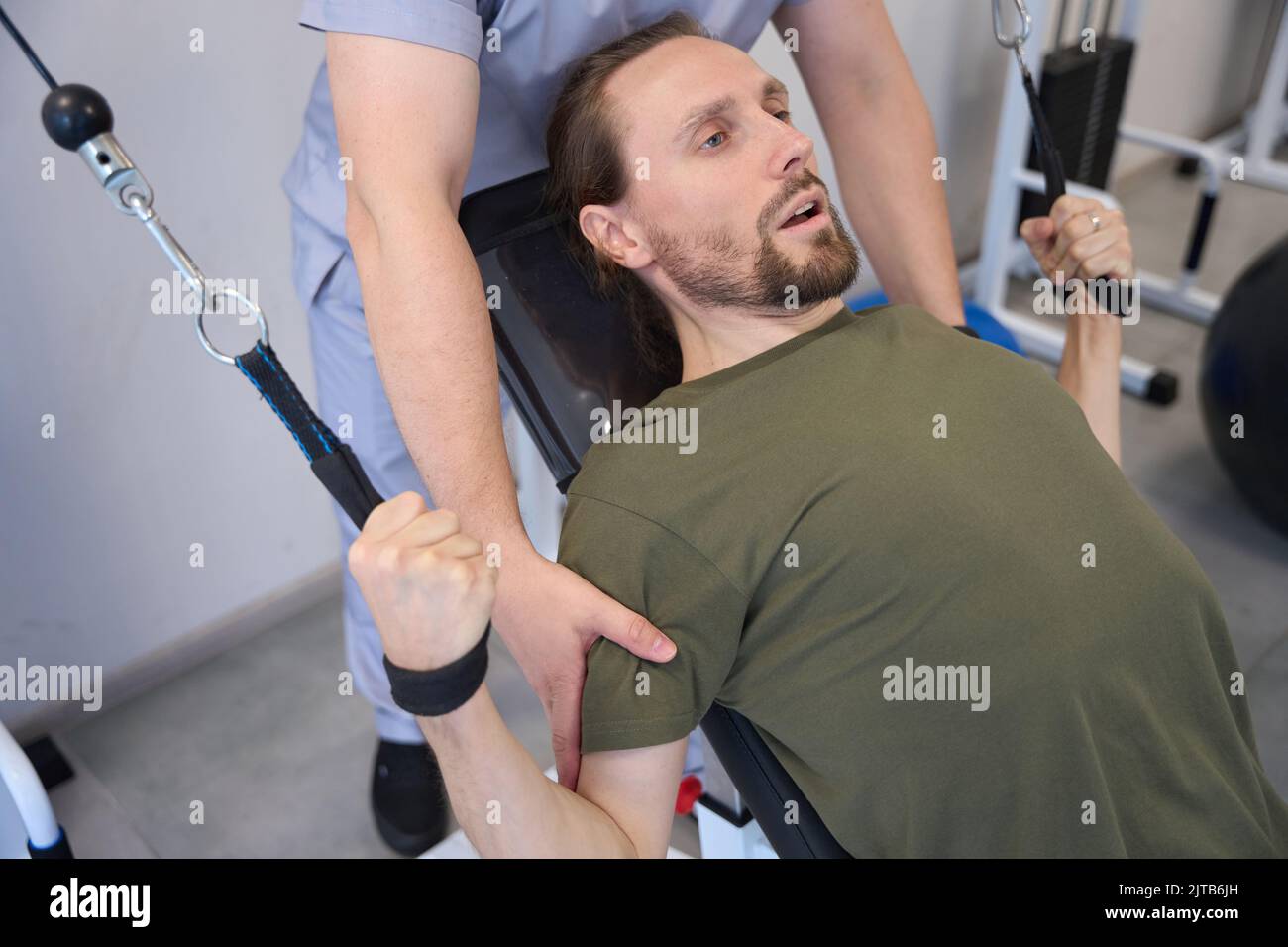 Weakened man is engaged in special equipment under supervision doctor Stock Photo