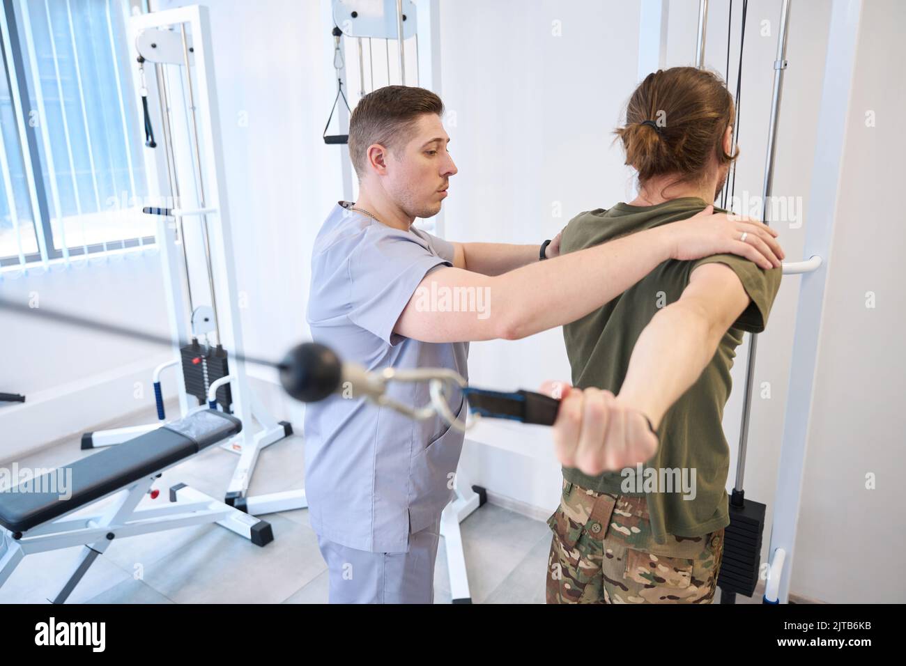 Iinstructor helps soldier on physiotherapy exercises in rehabilitation center Stock Photo