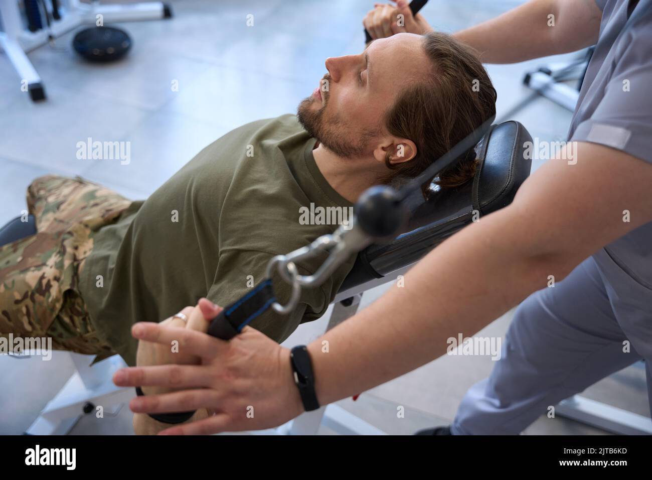 Soldier after being wounded is engaged in simulator with doctor Stock Photo