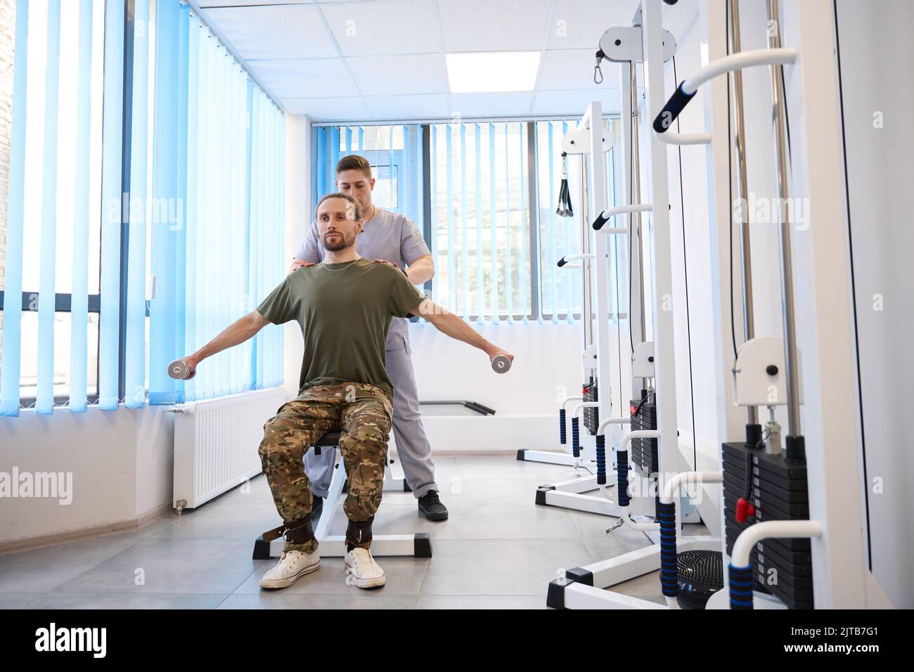 Instructor helps soldier recover from injury in military hospital Stock Photo