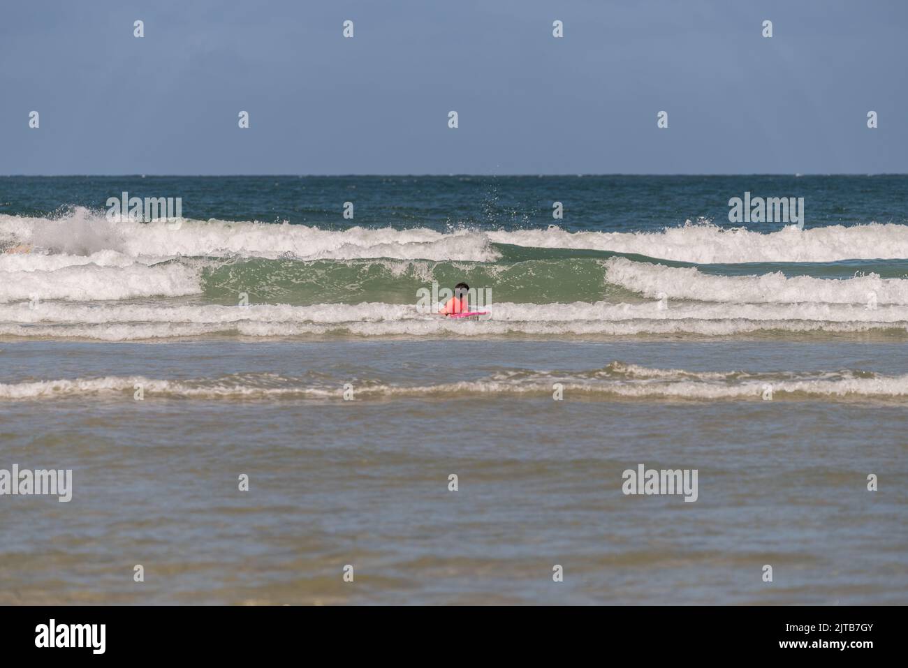 boy with orange equipment and bodyboard practices in the waves of Aveiro beach Stock Photo