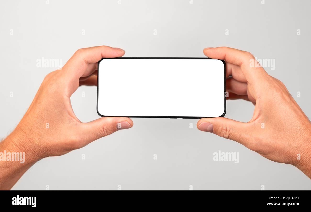 Man holding phone mockup in horizontal position. Male using smartphone for watching video. template with empty screen. High quality photo Stock Photo