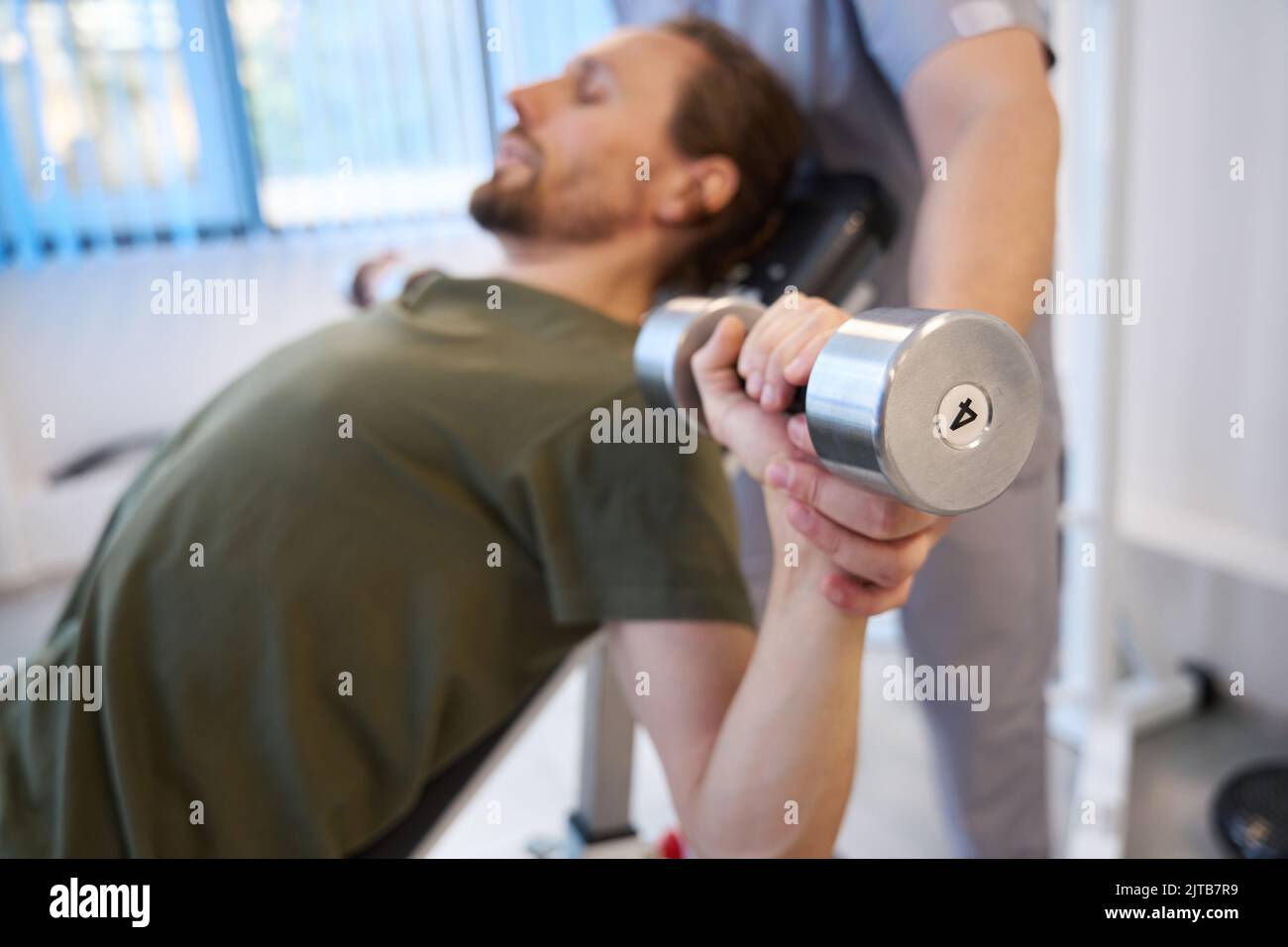 Man performs exercises with dumbbells with the help of physiotherapist Stock Photo