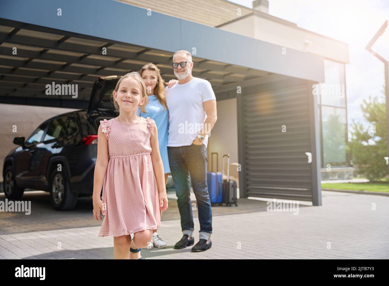 Smiling couple with daughter stand in front of new house Stock Photo