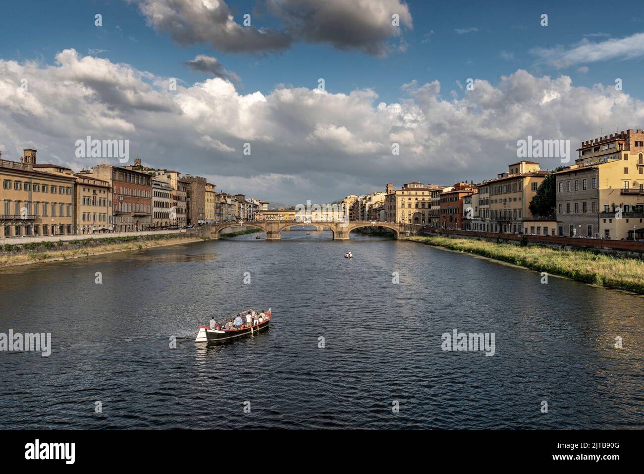 View of Florence with 'Ponte Vecchio' in the background and tourists sailing on the Arno river Stock Photo