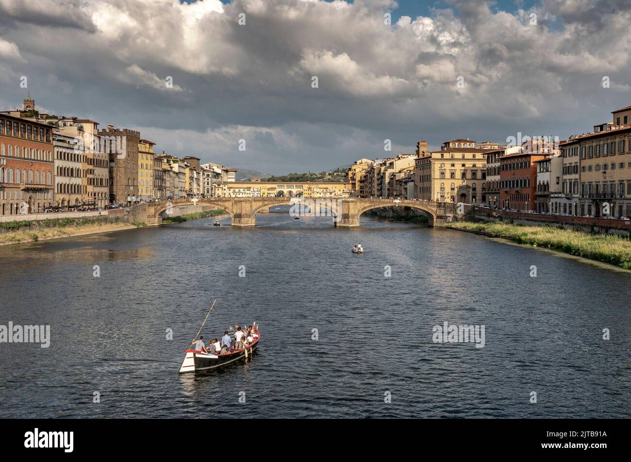 View of Florence with 'Ponte Vecchio' in the background and tourists sailing on the Arno river Stock Photo
