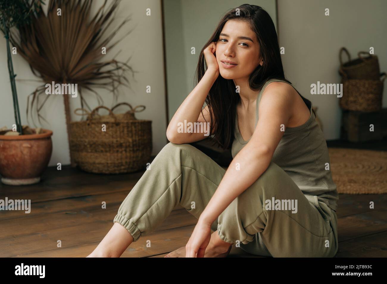 Portrait of a serene beautiful young brunette woman sitting on the floor. Stock Photo