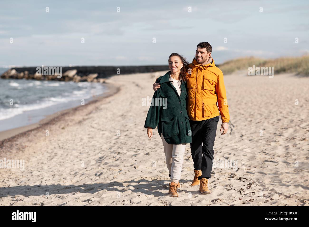 couple walking along autumn beach Stock Photo - Alamy