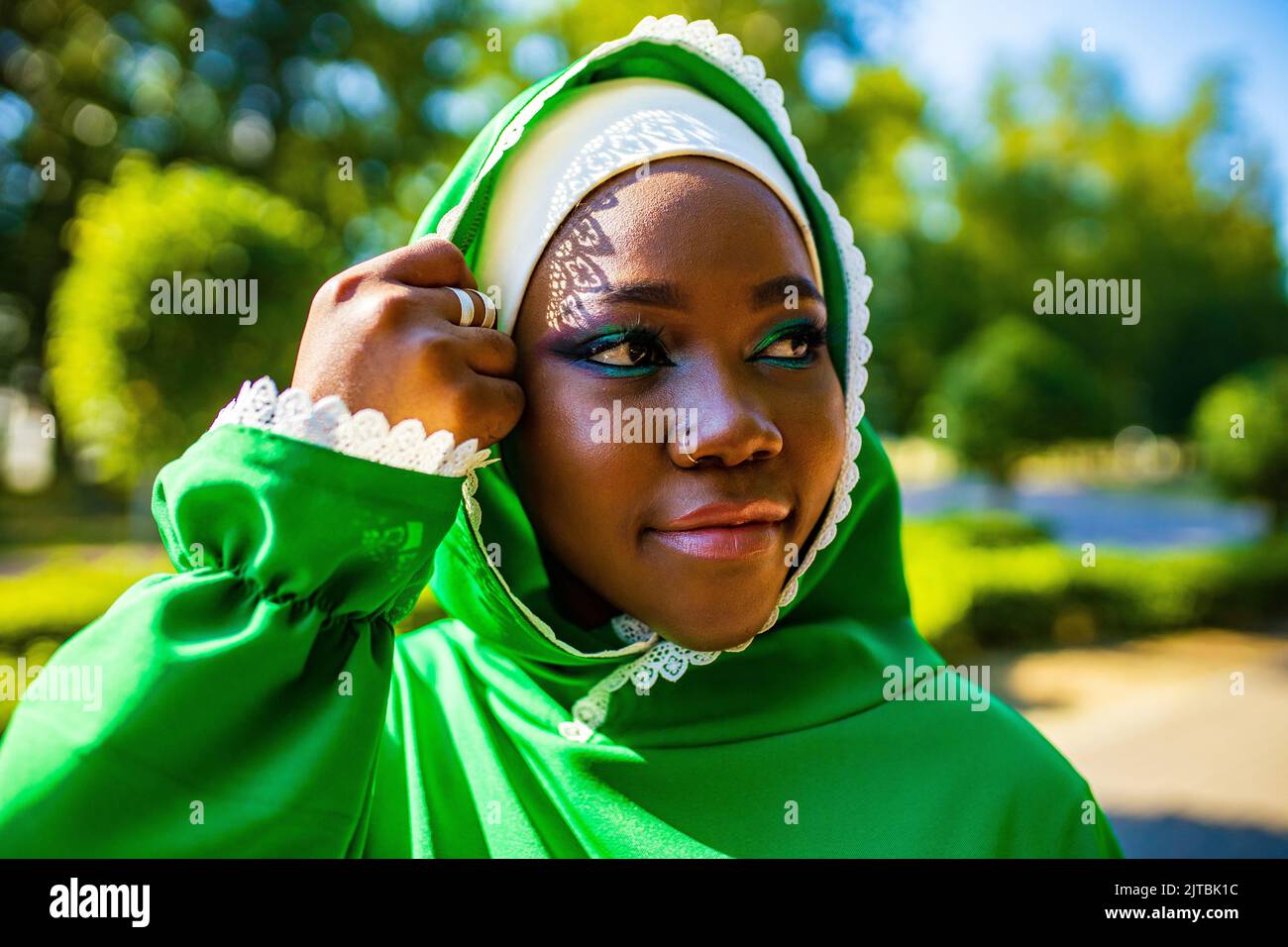 modern authentic multicultural race islamic woman in green cotton hijab with gorgeous make up outdoors in summer park Stock Photo