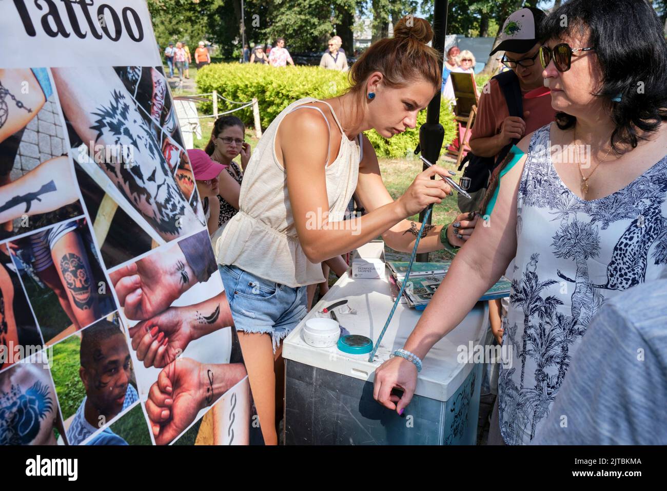 Girl is making tattoo on woman's arm in Carnikava city festival, Carnikava, Latvia Stock Photo