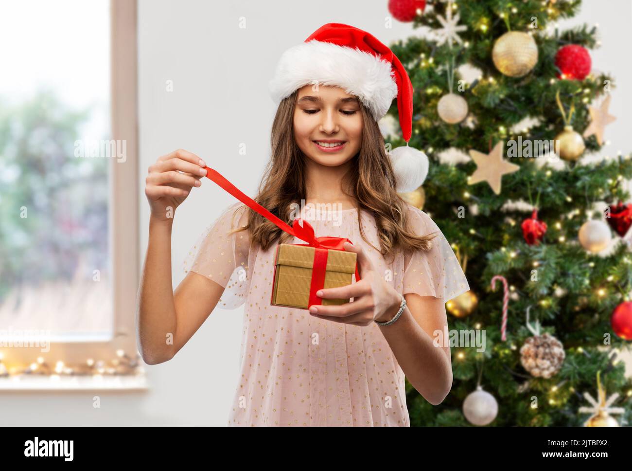 Teenage girl opening christmas gift hi res stock photography and