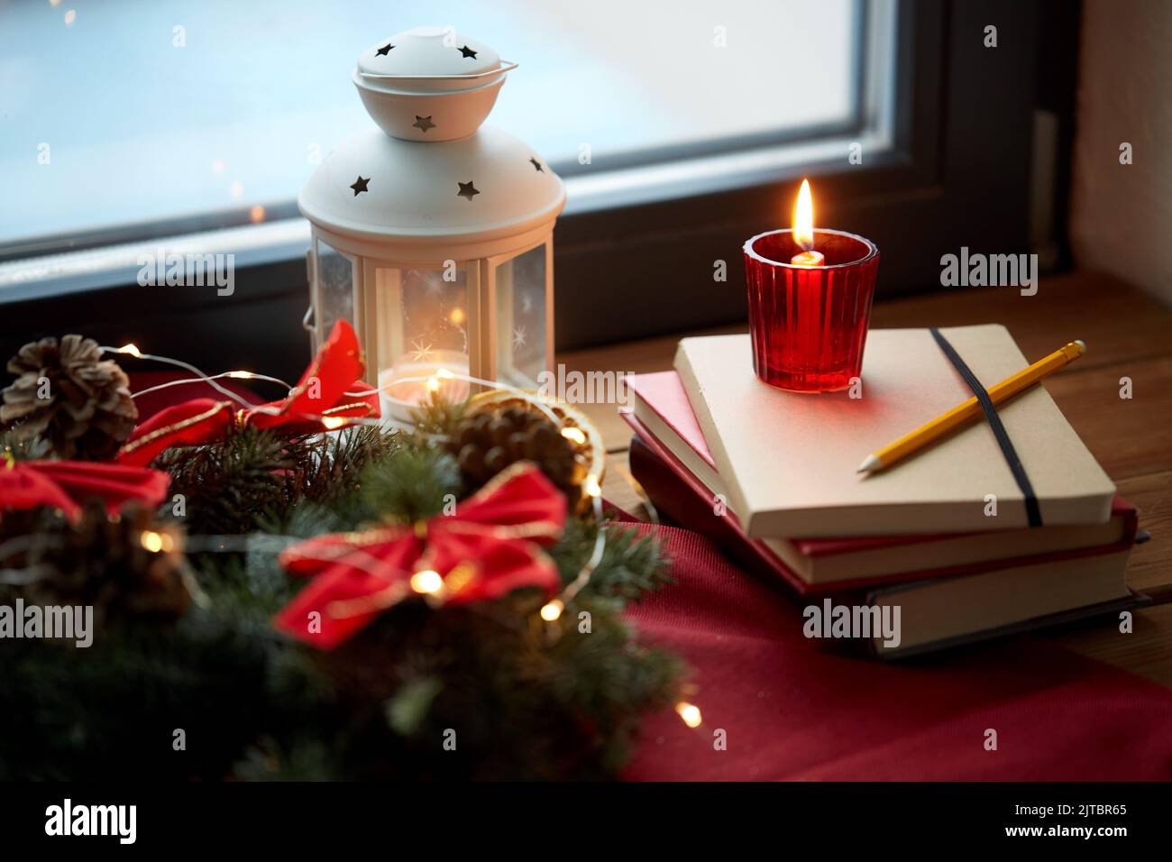 christmas wreath, books, candle, lantern on window Stock Photo Alamy