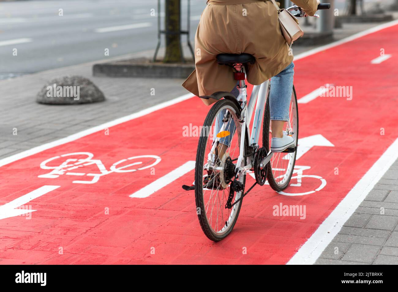 woman cycling along red bike lane road in city Stock Photo