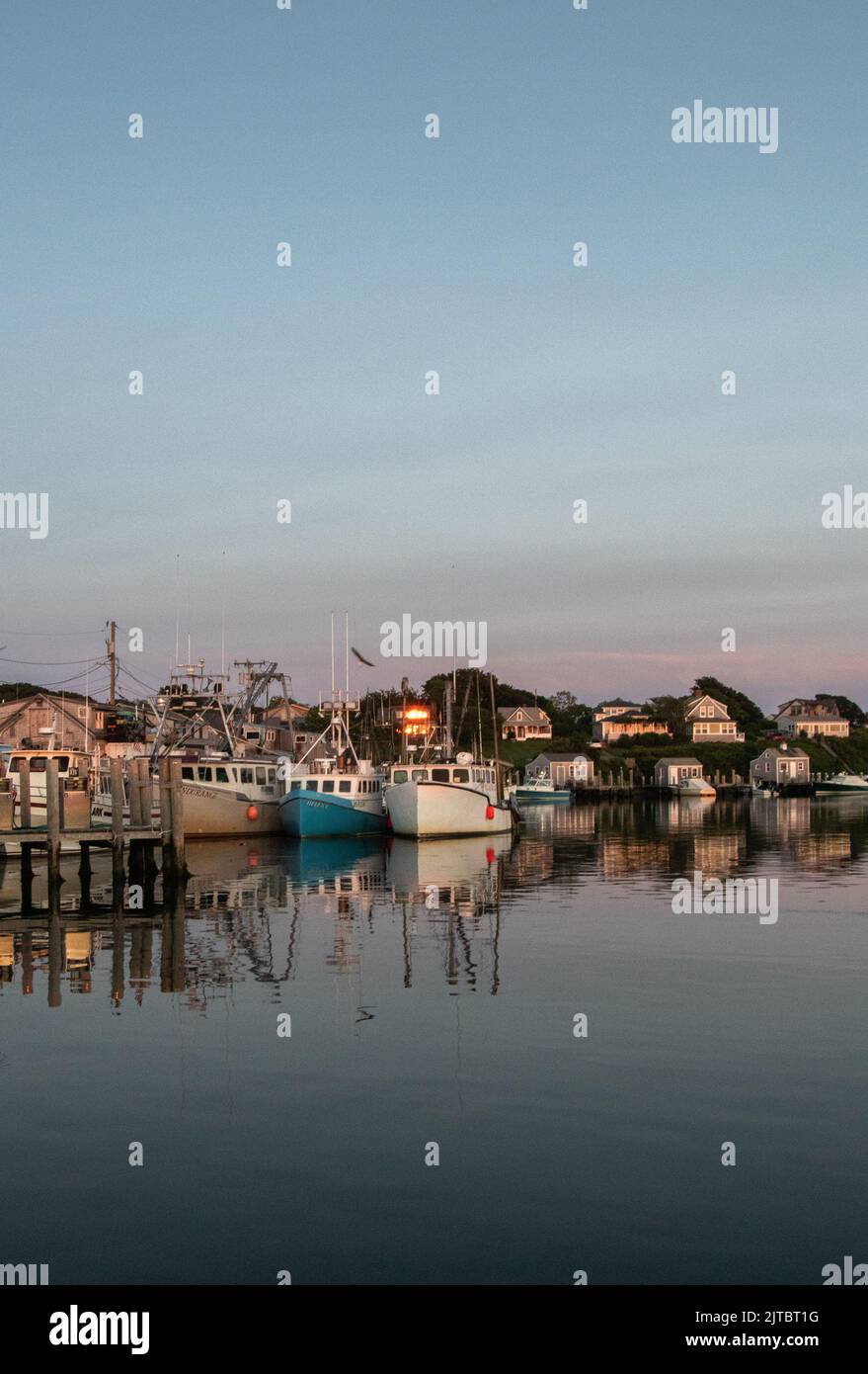 A vertical shot of commercial fishing boats at sunset in a harbor on ...