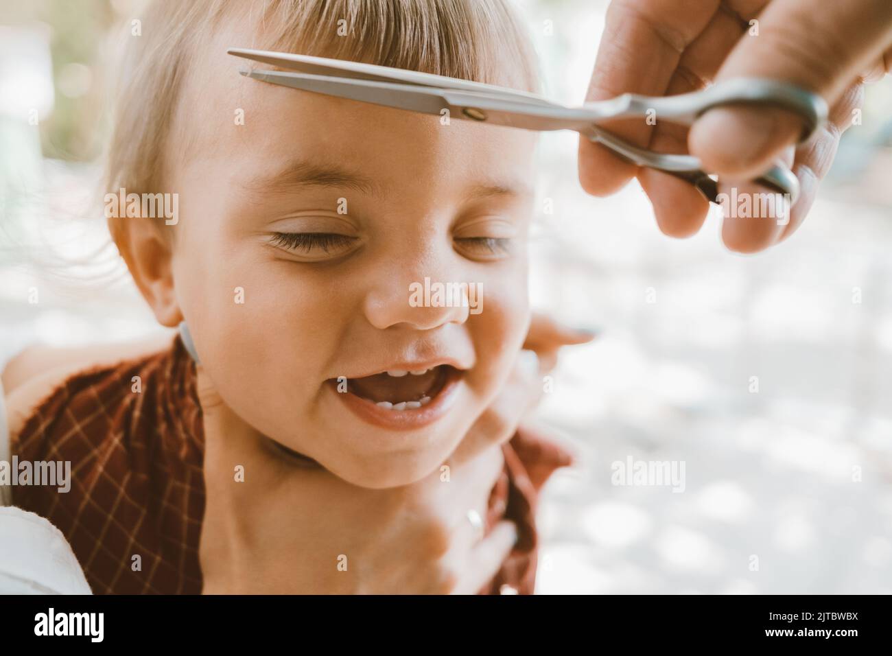 First haircut of little baby boy at home by parents. Cute funny