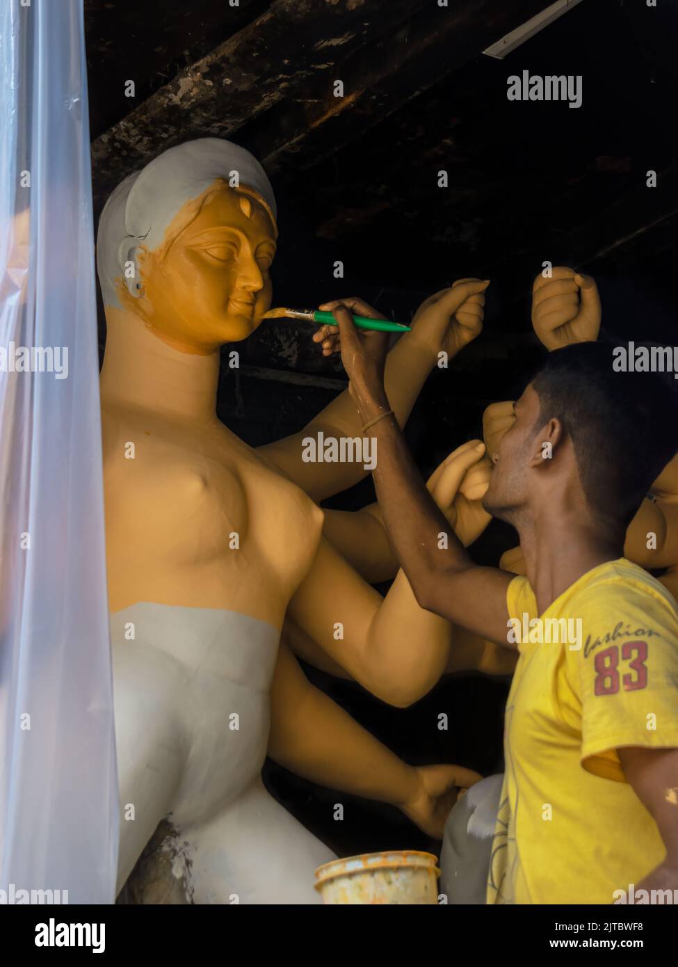 Kolkata, India - August 28, 2022: A man putting color on clay idol of Devi Durga for the upcoming Durga Puja festival. Selective Focus on face of idol Stock Photo