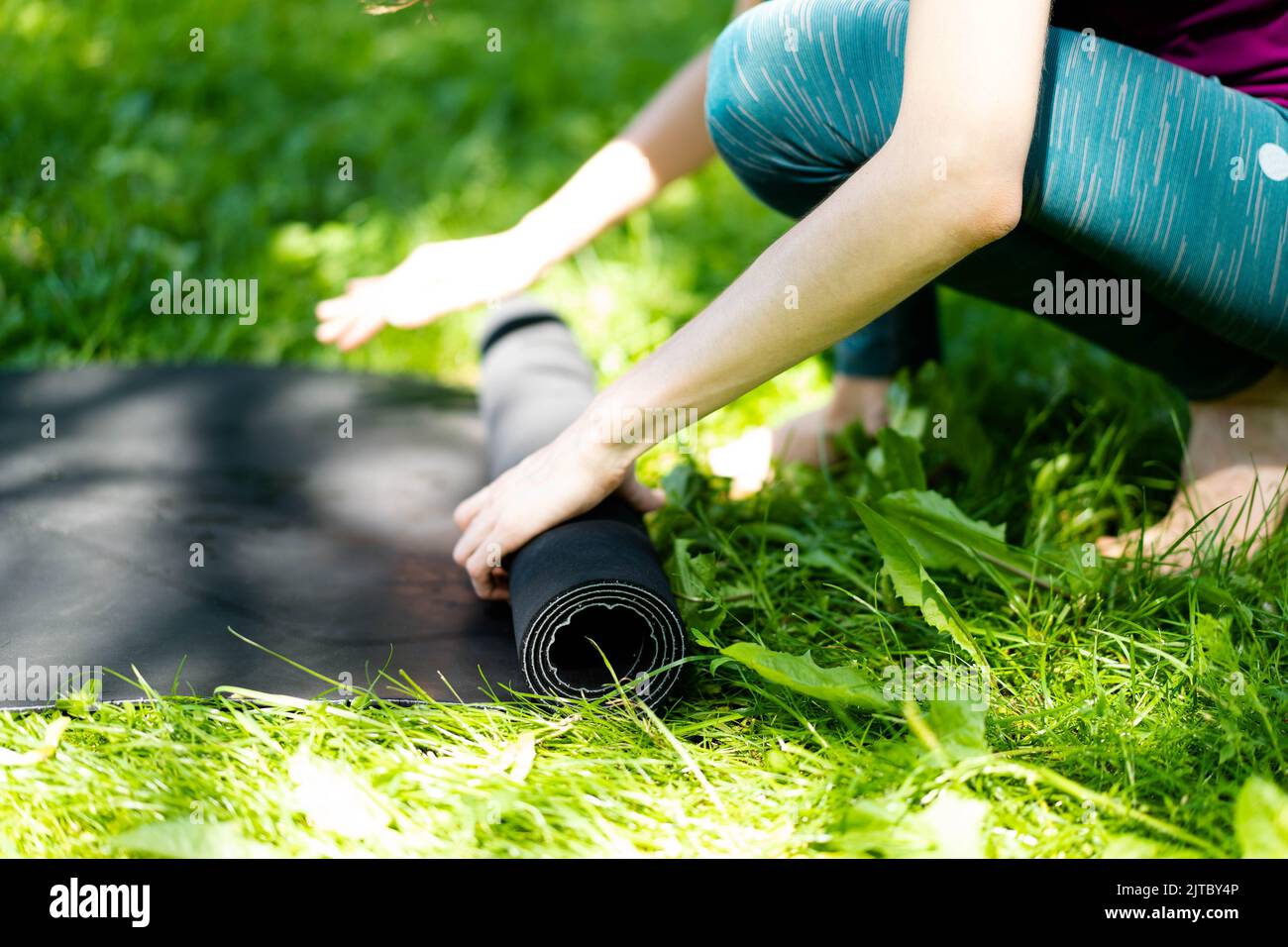 Banner Woman hands rolled up yoga mat outdoor workout. Yoga exercises in the morning in the park. Woman stretching workout , close-up, copyspace Stock Photo
