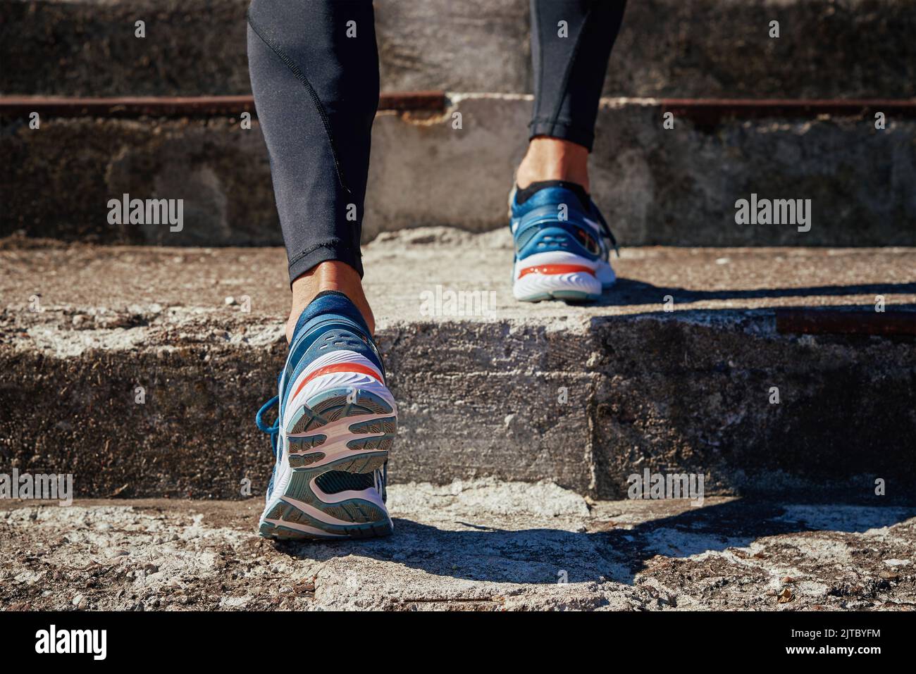 Male sprinter wearing running shoes at concrete stairs background