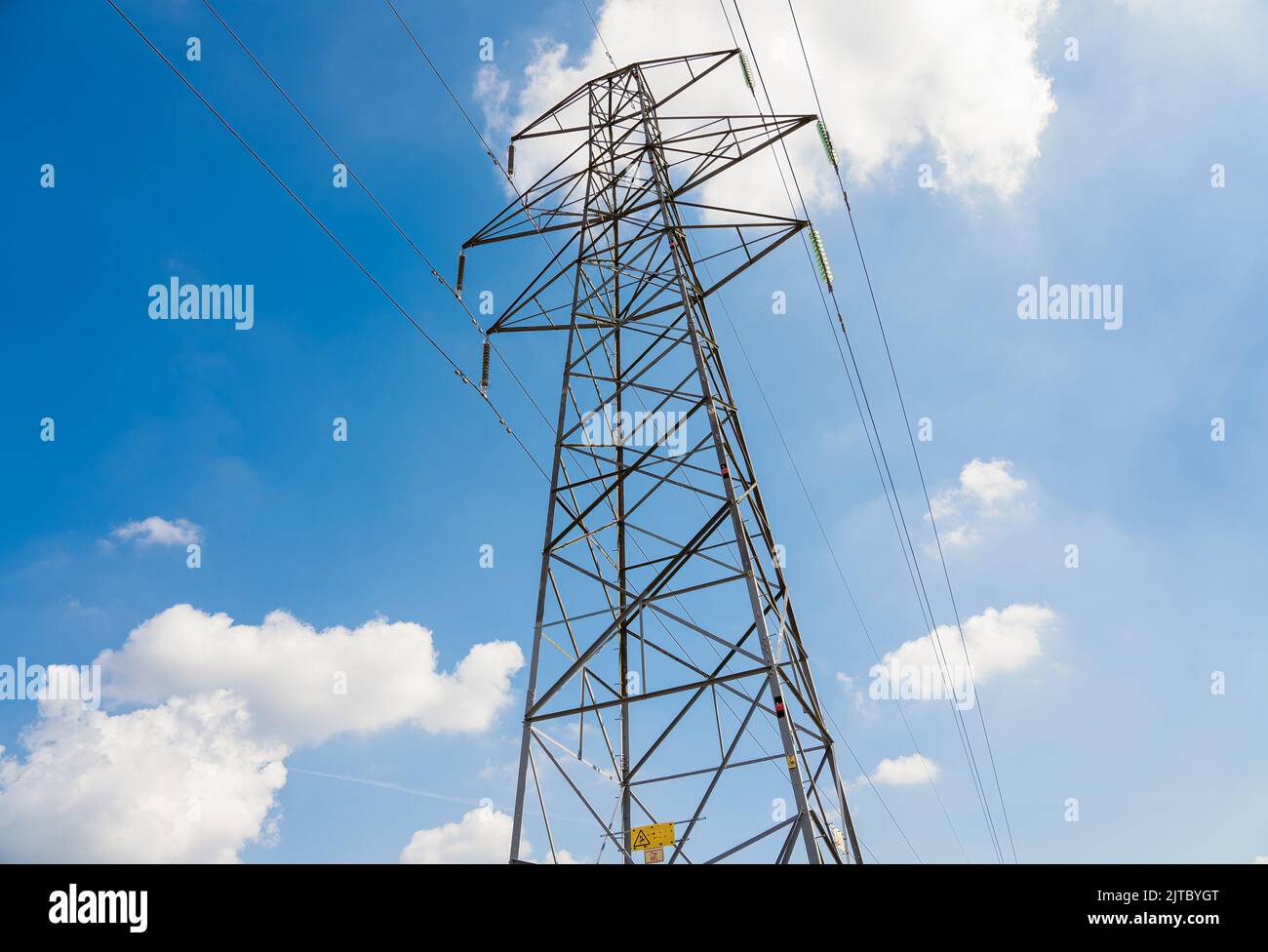 close-up of electricity power pylon and cables against a bright blue ...