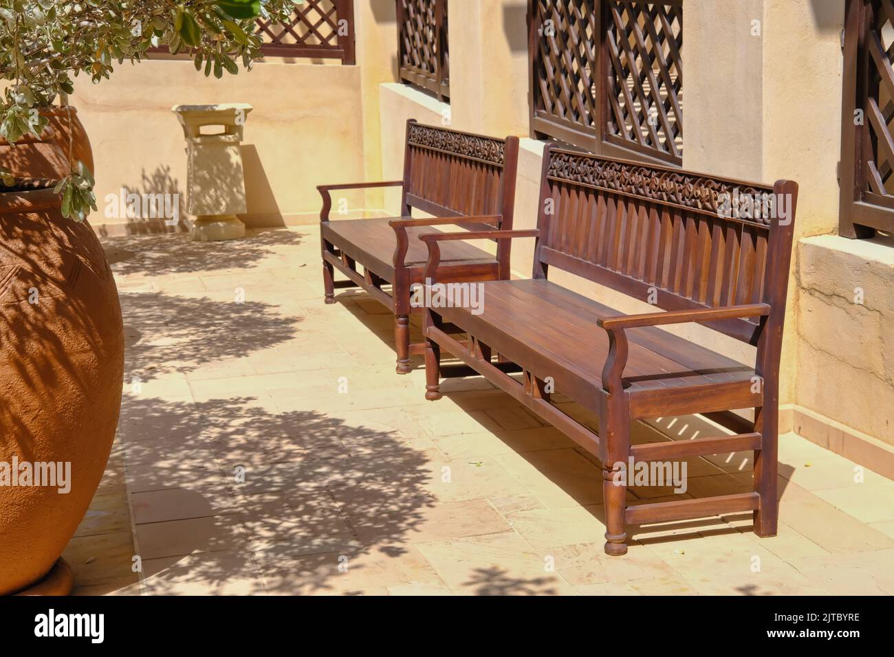 Orient wooden bench handmade with carved ornamental arabesque floral pattern in inner courtyard of middle eastern villa Stock Photo
