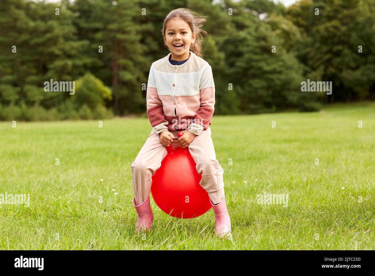 happy little girl bouncing on hopper ball at park Stock Photo Alamy