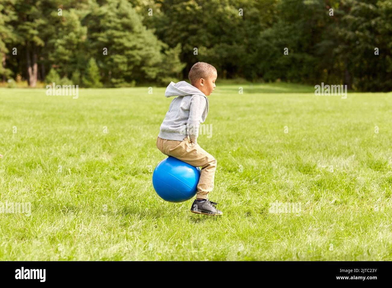 happy little boy bouncing on hopper balls at park Stock Photo