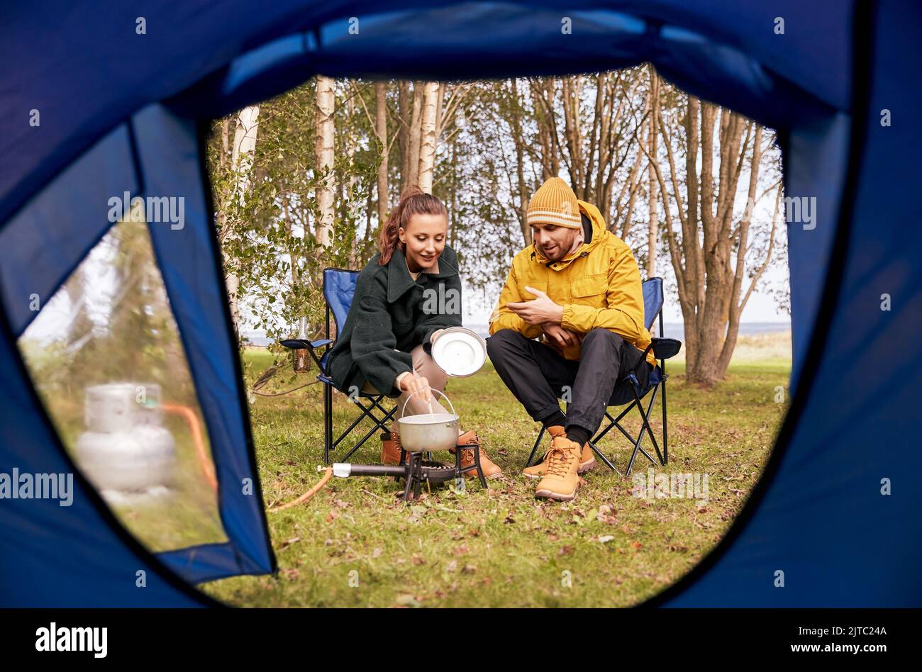 couple cooking food on gas burner at tent camp Stock Photo Alamy