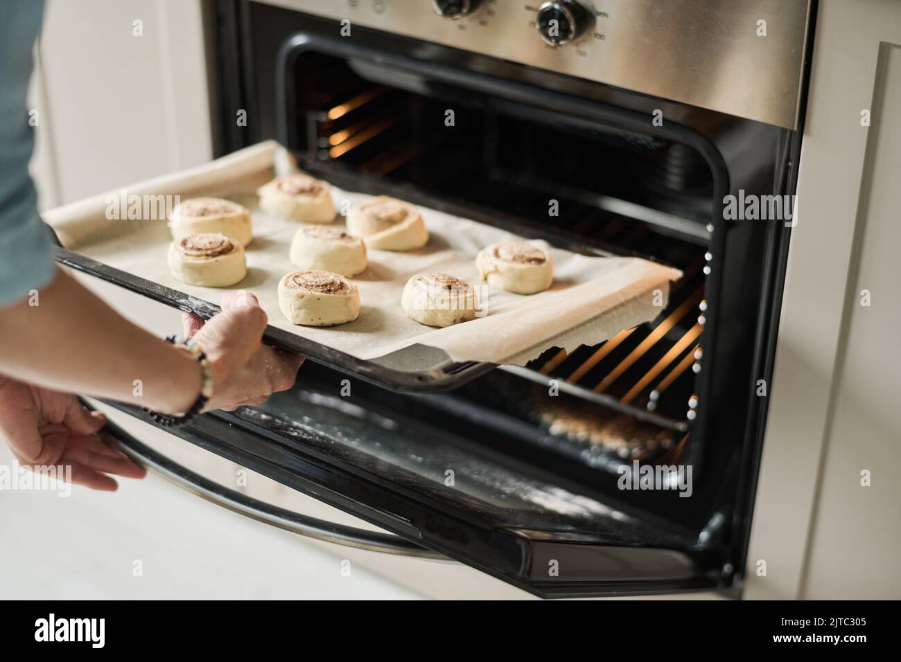 Close-up of young woman baking sweet buns in oven at home Stock Photo