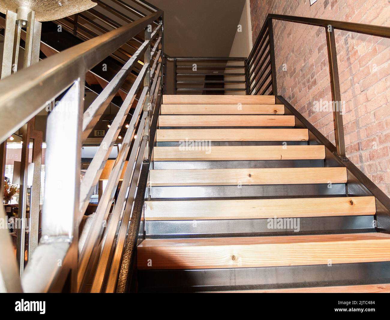Steel staircase frame with wooden risers and steps leading to landing with handrails. Stock Photo