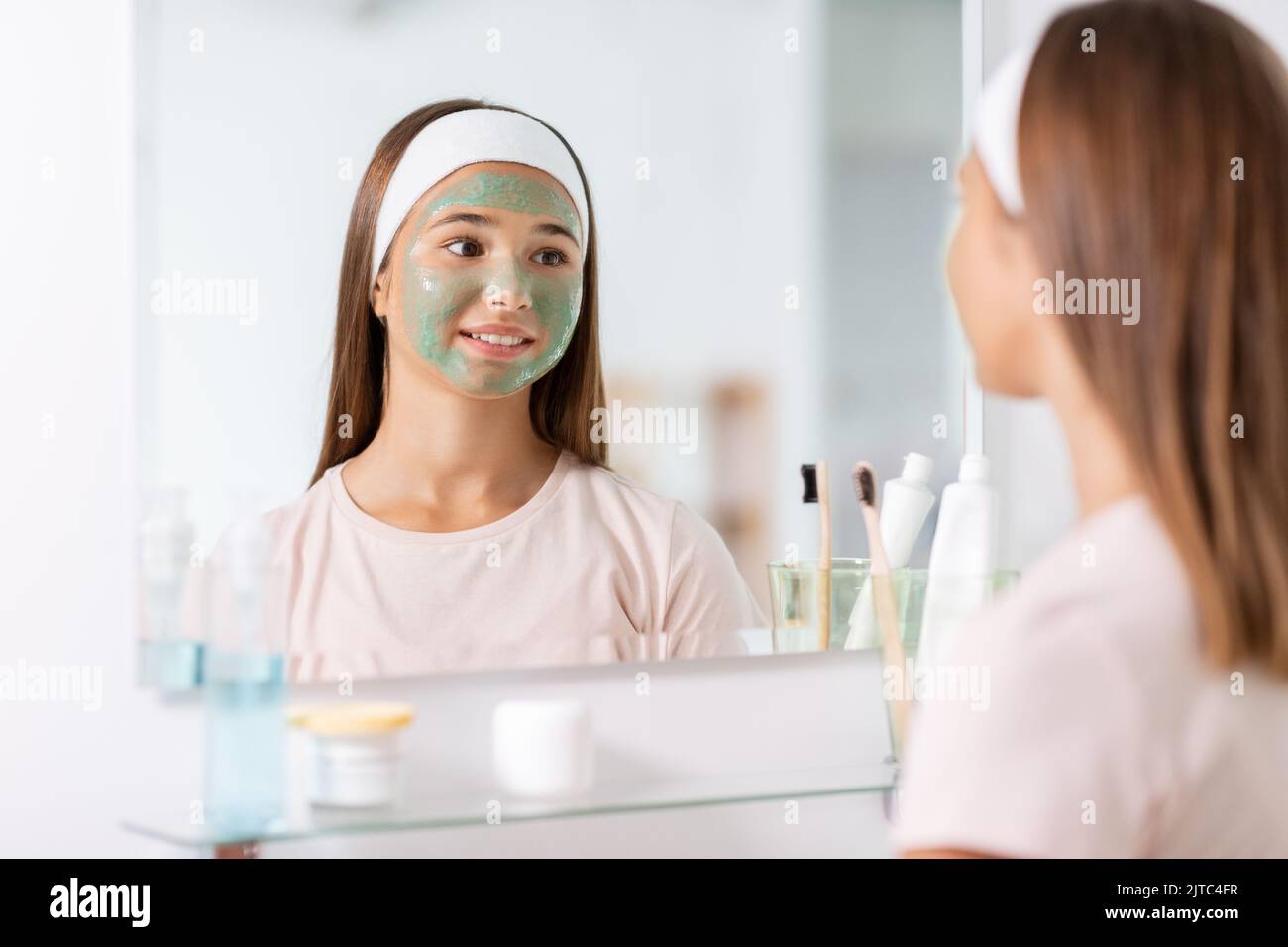girl with clay mask on face looking in mirror Stock Photo Alamy