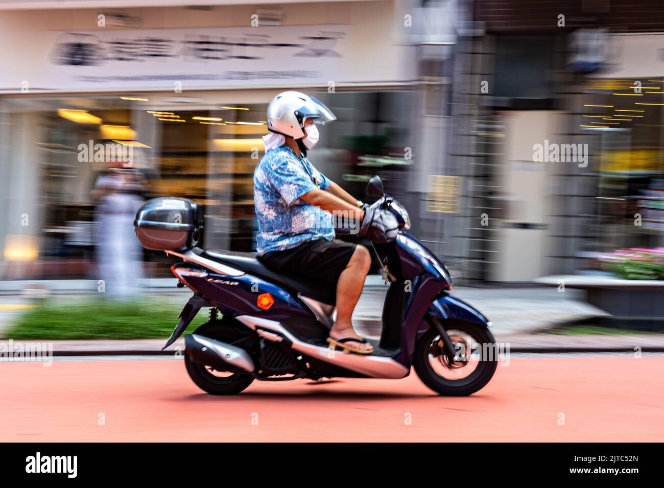 A man rides an electric scooter down Orange Street near the Sensoji temple in Asakusa, Tokyo, Japan. Stock Photo