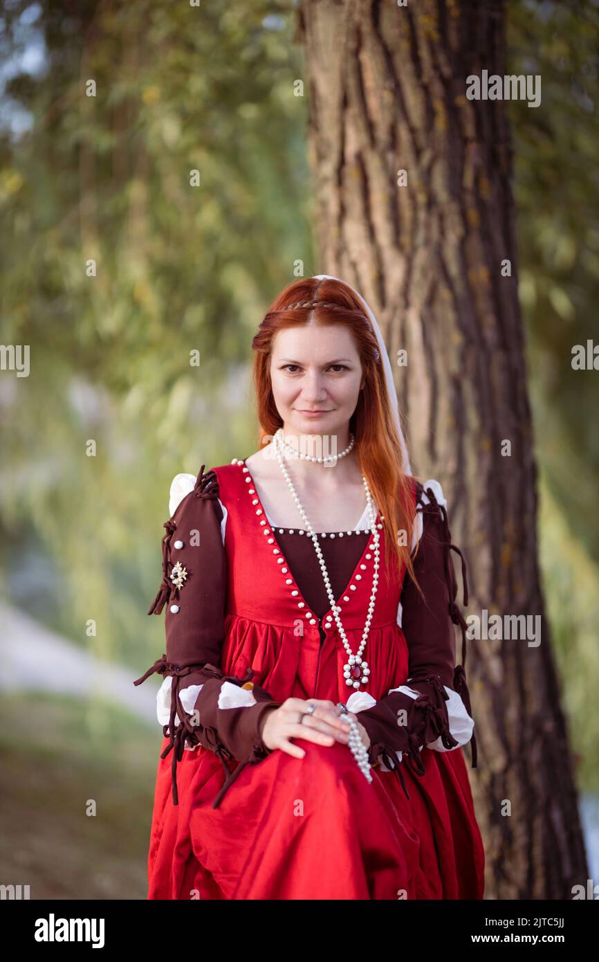 Red-haired slender girl in a red dress in the Venetian fashion of the ...