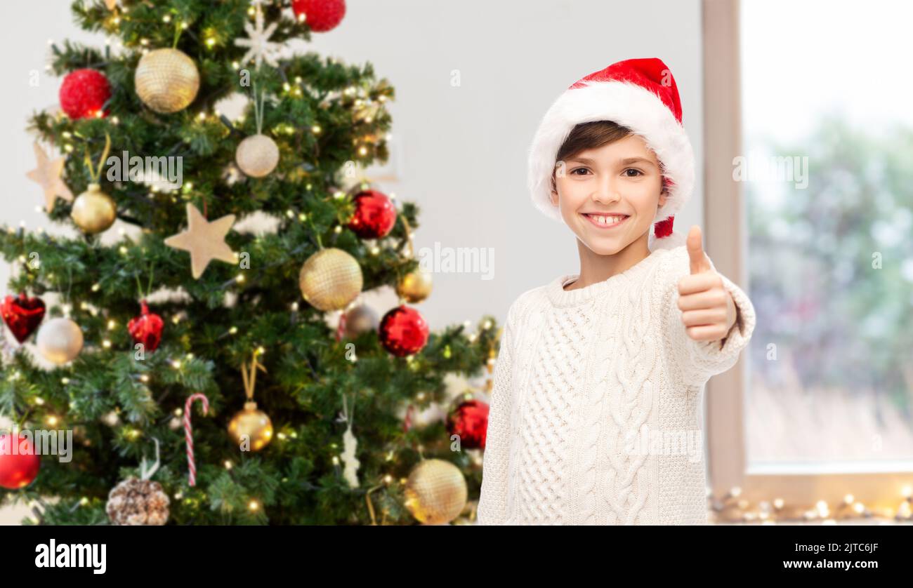 happy boy showing thumbs up over christmas tree Stock Photo - Alamy