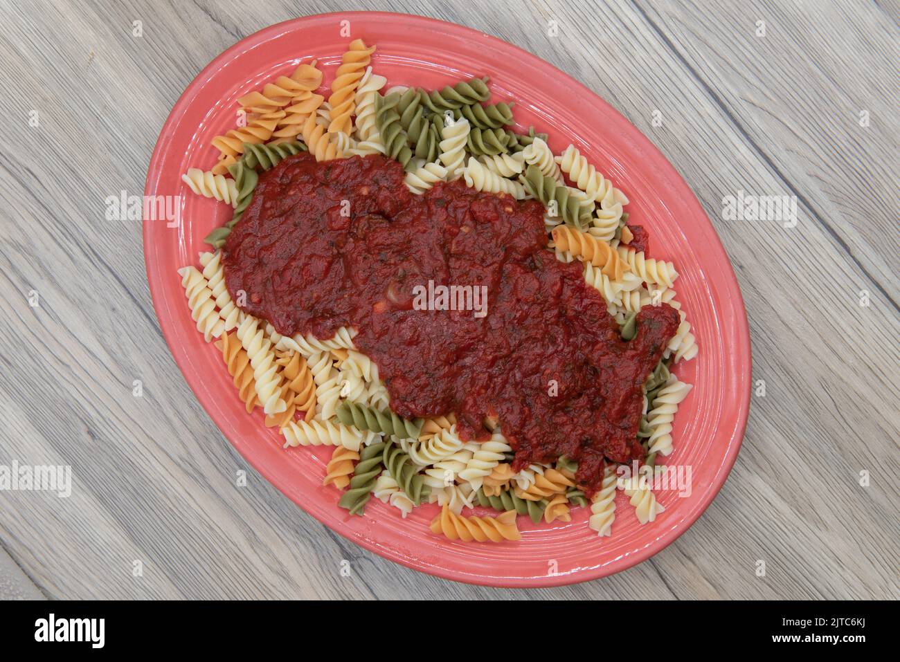 Overhead view of rotelli pasta smothered in authentic Italian marinara sauce and generously served on an oval plate. Stock Photo