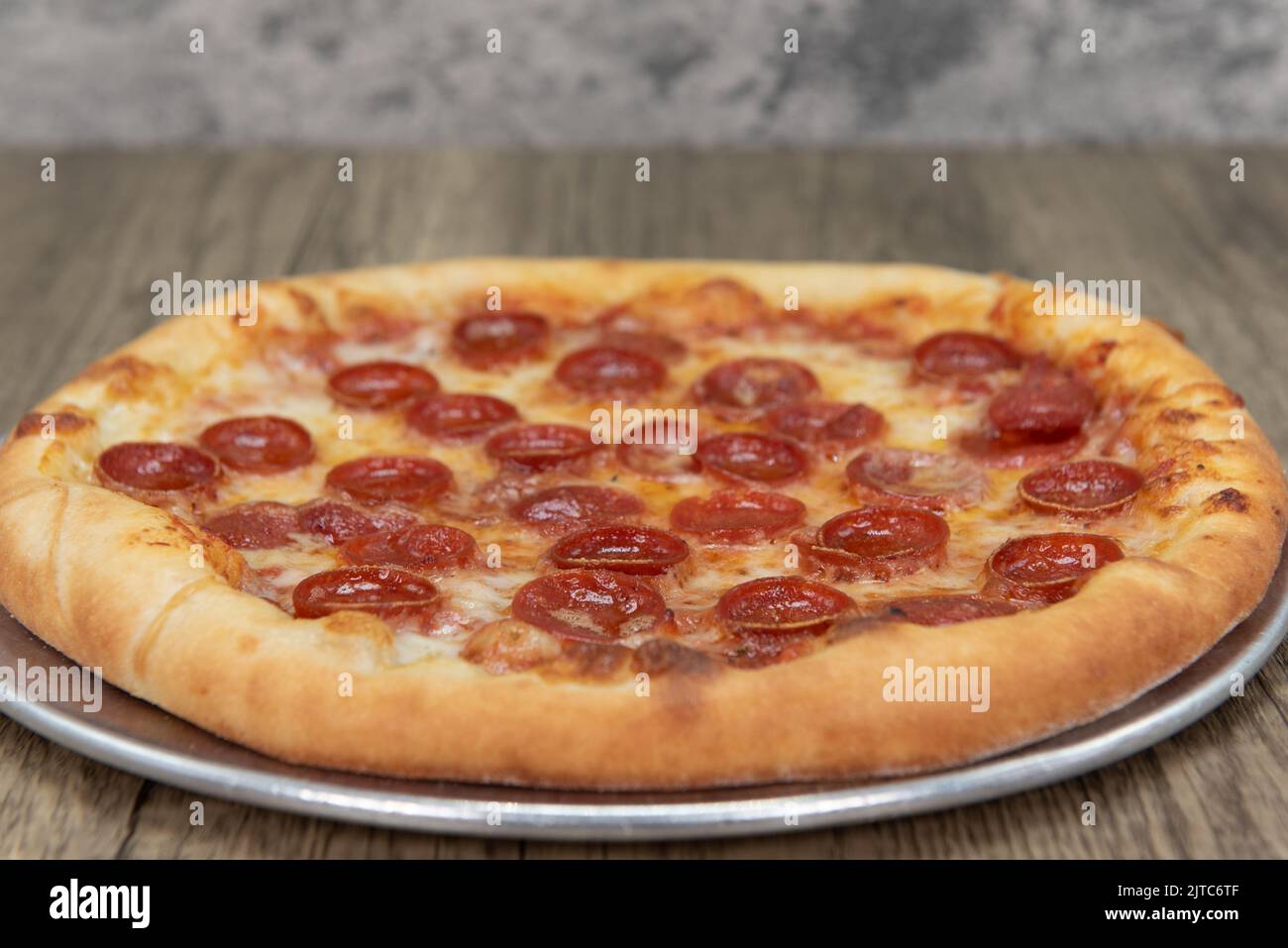 Hot from the oven is a crispy crust Italian baked pepperoni pizza that is ready to eat. Stock Photo