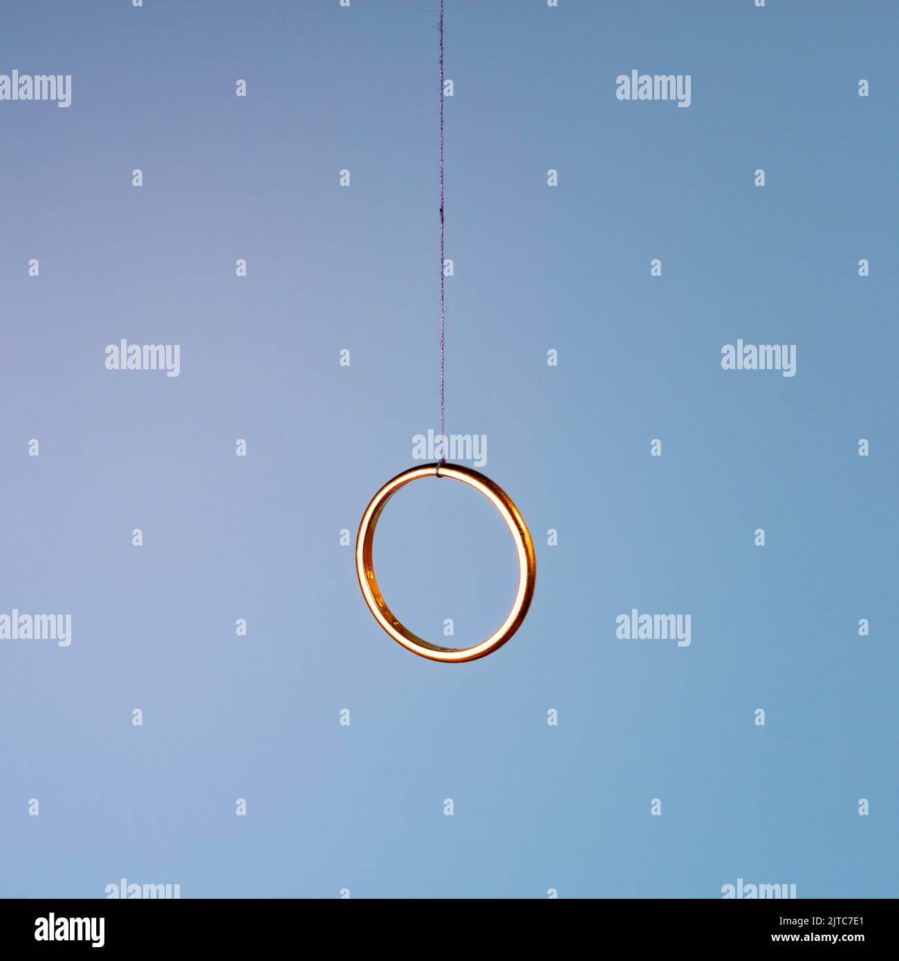 The crisis of marriage. A wedding ring hanging by a thread. Stock Photo