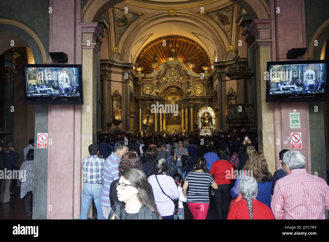 People gathering to hear Mass at Las Nazarenas church, TV monitors are for people outside. Stock Photo