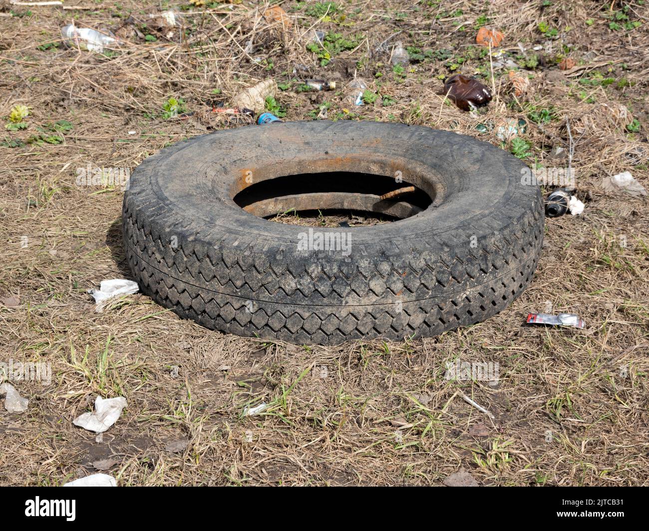 A worn car tire is wallowing in mud and a puddle on the ground