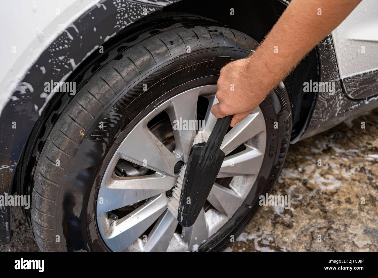 man's hand cleaning the rims of a car with a brush Stock Photo
