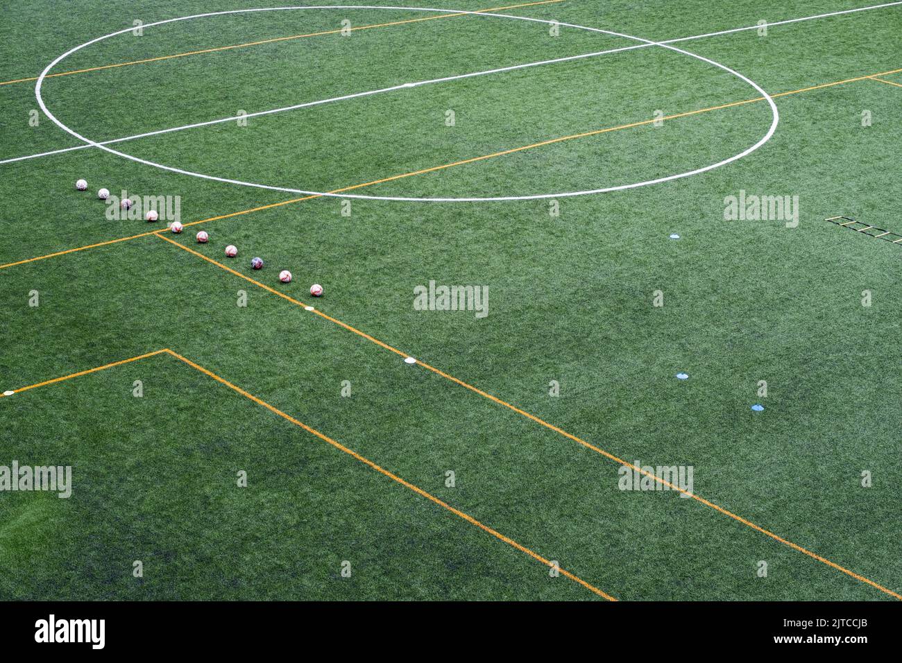 Soccer balls lined up on the field before the local team's practice session. Equipment for the training session on the surface of an artificial turf. Stock Photo