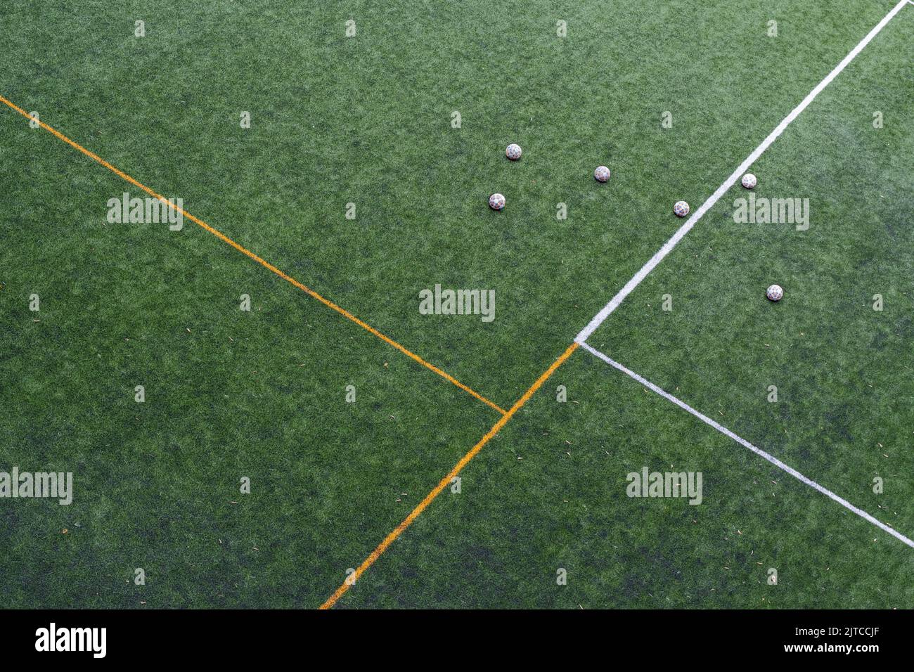 Soccer balls left on the field after a practice session of the local team. Artificial turf field, sports ball. Top view. Stock Photo