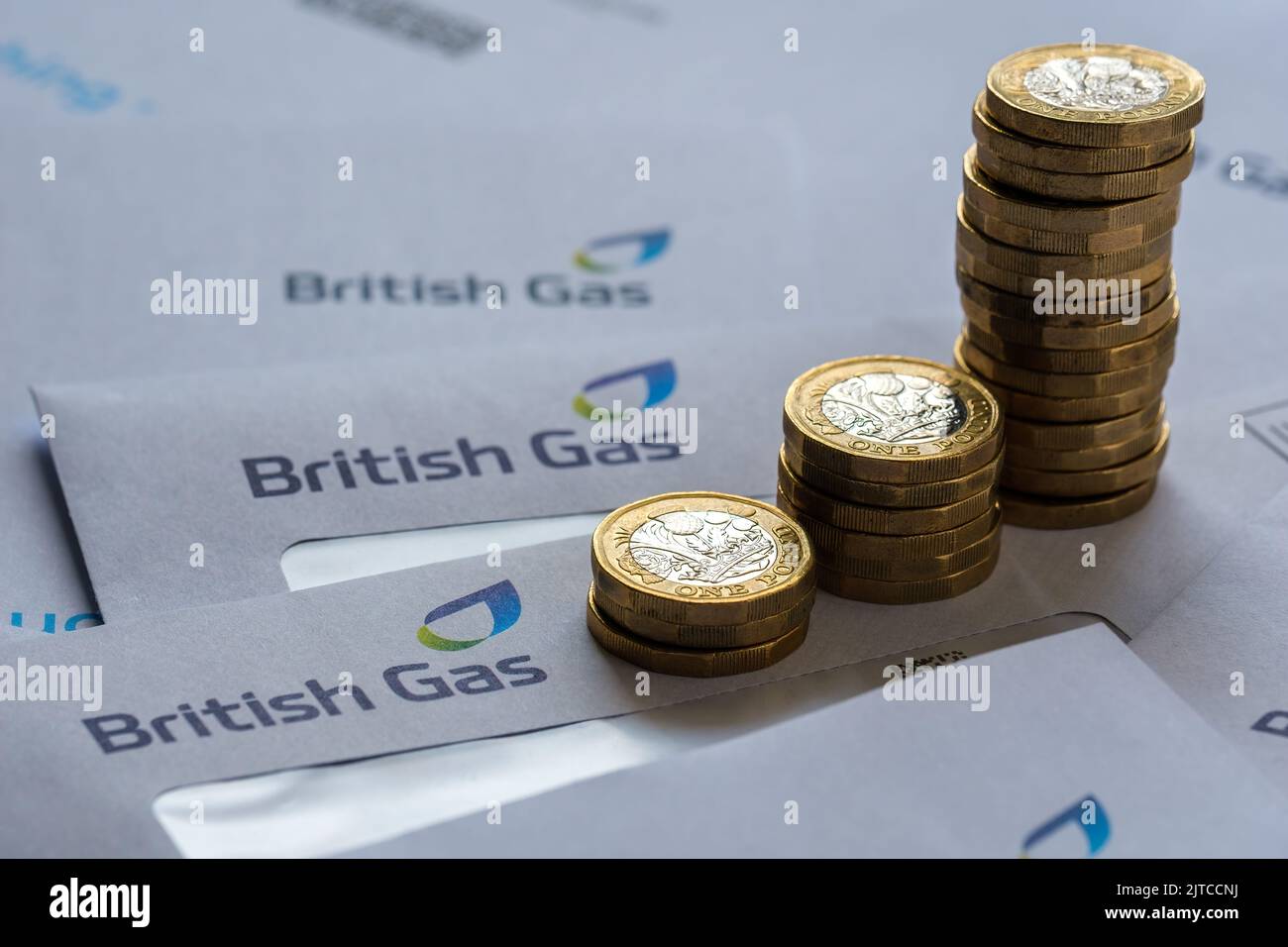Stacks of One Pound coins on top od British Gas bills in the envelopes. Concept for energy crisis and rising gas prices in the UK. Stafford, UK, Augus Stock Photo