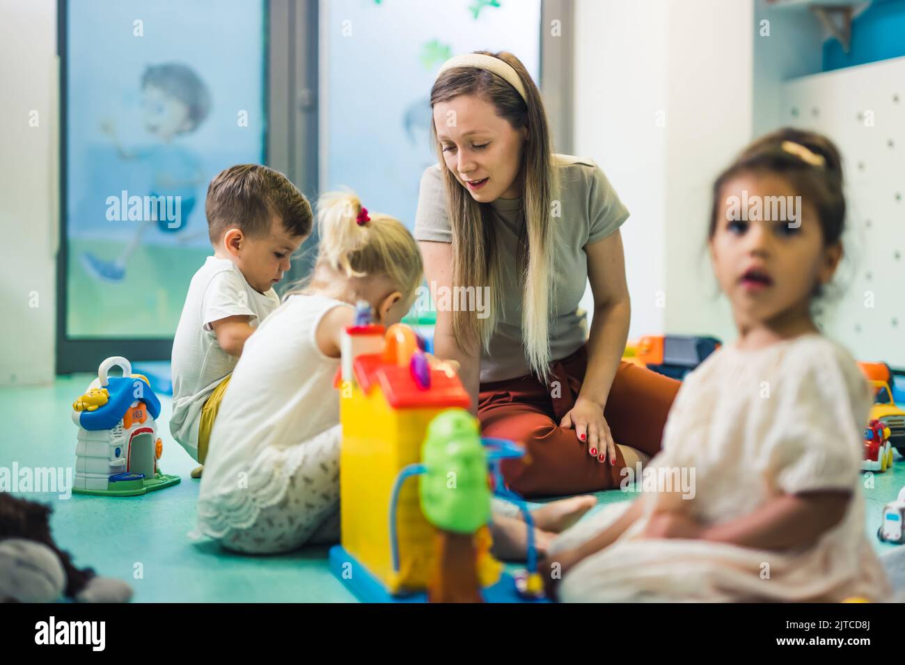 Nursery school. Toddlers and their teacher playing with colorful
