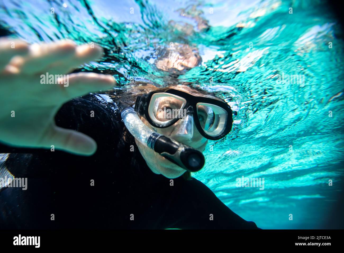 young woman in wet suit snorkling off the coast of Hopkins in Belize Stock Photo