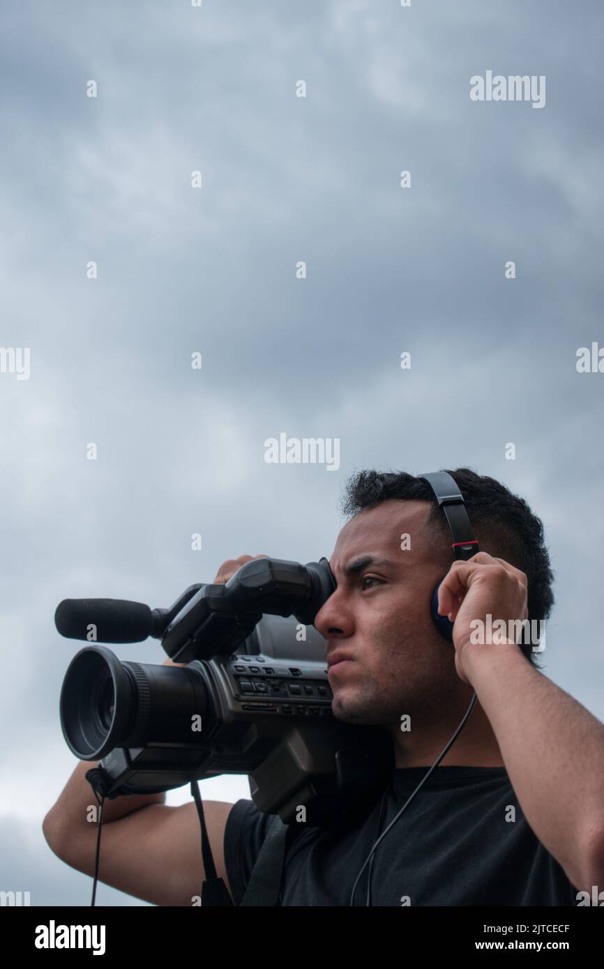 Man filming with a big video camera in a cloudy day Stock Photo