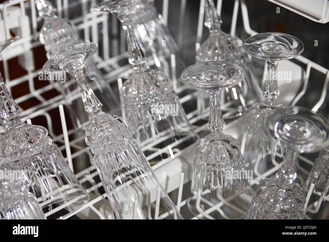 Image of some fine crystal glasses for wine and champagne in the tray of a dishwasher in which they have been cleaned Stock Photo