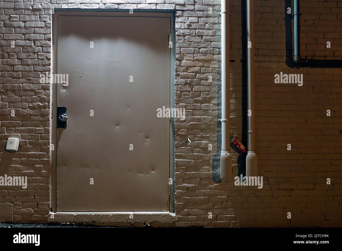 White Metal Door and White Brick Wall Exterior at Night Stock Photo